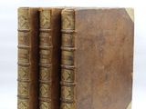 two old books sitting on top of each other on a white surface