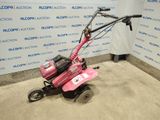 the small pink mower is parked in front of a wall