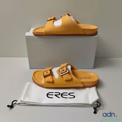une image représentant une paire de sandales jaunes posées sur une boîte blanche