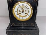 une image représentant une horloge noire et dorée posée sur une table