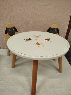 une petite table avec deux chaises et un mouton dessus
