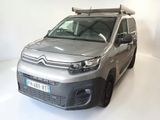une camionnette Citroën garée dans une pièce blanche, avec une planche de surf sur le toit