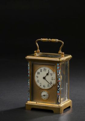 une petite horloge munie d'une poignée, posée sur un fond noir