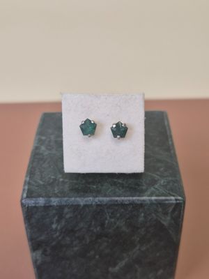 a pair of green earrings sitting on top of a marble block