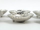 three silver plated bowls with handles and feet on a white surface