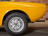 a yellow car that is parked in front of a brick wall