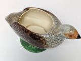 a ceramic bird that is sitting on top of a vase