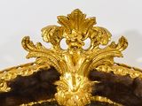 a gold clock on the top of a golden chair