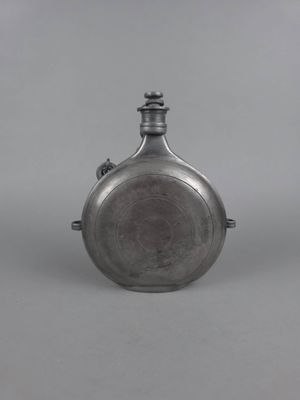 une flasque ancienne en argent munie d'une anse, sur fond gris