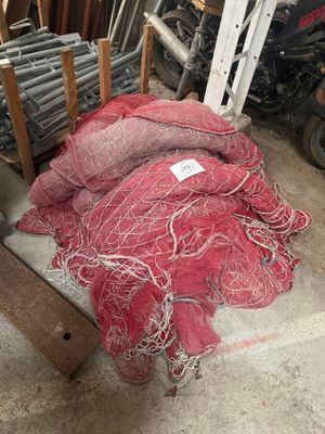 a pile of red netting on the ground next to a pile of motorcycles