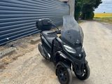 Le scooter est garé sur le bord de la route, à côté d'un immeuble.