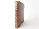 an old book sitting on top of a white table next to a white wall
