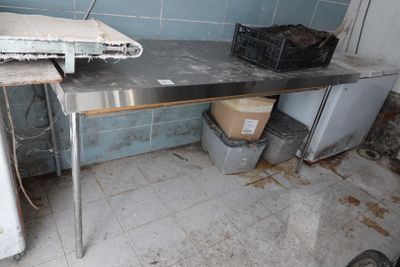 une table en métal avec un plateau en métal, dans une pièce sale