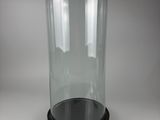 a glass clochet with a black base on a table