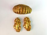 deux bijoux en or posés sur une surface blanche