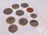 une vitrine transparente contenant des pièces de monnaie, posée sur une surface blanche
