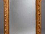 an ornately carved mirror with a gold frame on a grey background