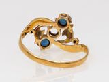 an image of a gold ring with blue stones on a white surface