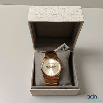 Une montre Michael Korsch dans son coffret, posée sur une table blanche