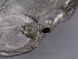 a close up of a silver vase with a bird on it