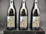trois bouteilles de vin posées sur un bloc de bois