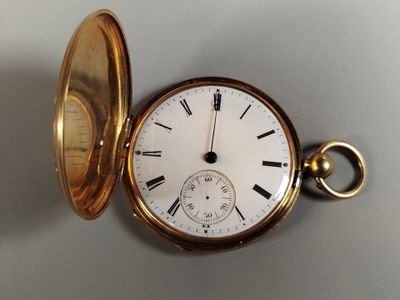 une montre de poche en or posée sur une surface blanche