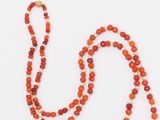 un collier de perles orange muni d'un fermoir doré, sur fond blanc