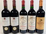 four bottles of red wine are lined up on a white surface