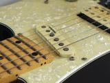 a close up of a black electric guitar on a table