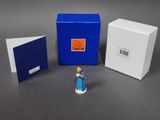 a small figurine of a woman standing next to a blue box