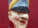 une figurine en céramique représentant un homme souriant coiffé d'un chapeau