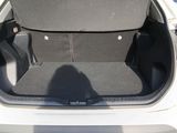 the back of a white car with its trunk open and the seat folded down