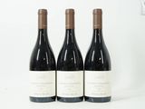 trois bouteilles de vin rouge sont alignées sur une surface blanche