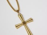 a gold cross pendant on a chain on a white background