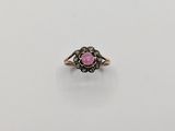 a gold ring with a pink stone surrounded by black diamonds
