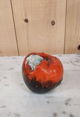 une pomme rouge et noire posée sur une table en marbre