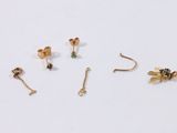 three pairs of gold earrings, one with a bee and one with a flower