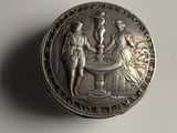 an old silver coin sitting on top of a table next to a cup