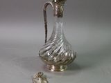 a silver and glass pitcher sitting on a table