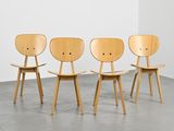 trois chaises en bois dans une pièce au sol en béton et aux murs blancs