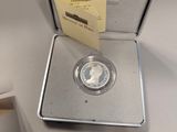 an image of a silver coin in a silver box with a note