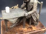 statue of a man sitting at a table with a candle in his hand