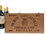 three bottles of wine in a wooden box next to a bottle of wine