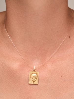 a close up of a woman wearing a gold necklace with a face on it