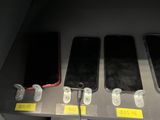 several cell phones are lined up on a shelf in a store
