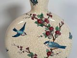 a vase with a bird design on it sitting on a table