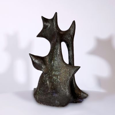 une sculpture en bronze représentant un chat assis sur une table