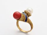 un gros plan sur une bague en or sertie d'une pierre rouge et d'une perle