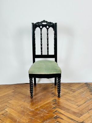 une chaise noire avec une assise verte posée sur un parquet