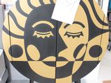 un soleil jaune et noir peint sur la façade d'une vitrine en bois